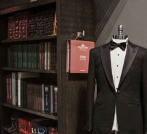 Mannequin in a tuxedo beside a bookshelf