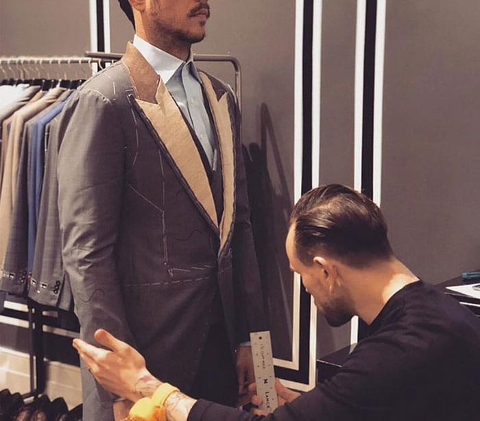 Man being measured for a bespoke suit by a tailor