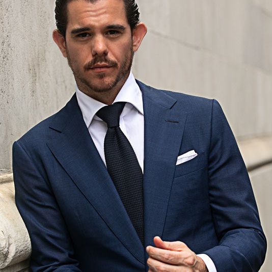 Man wearing a navy suit with a white shirt and dark tie