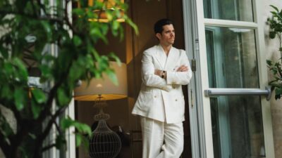 A man in doorway wearing a white loose suit,