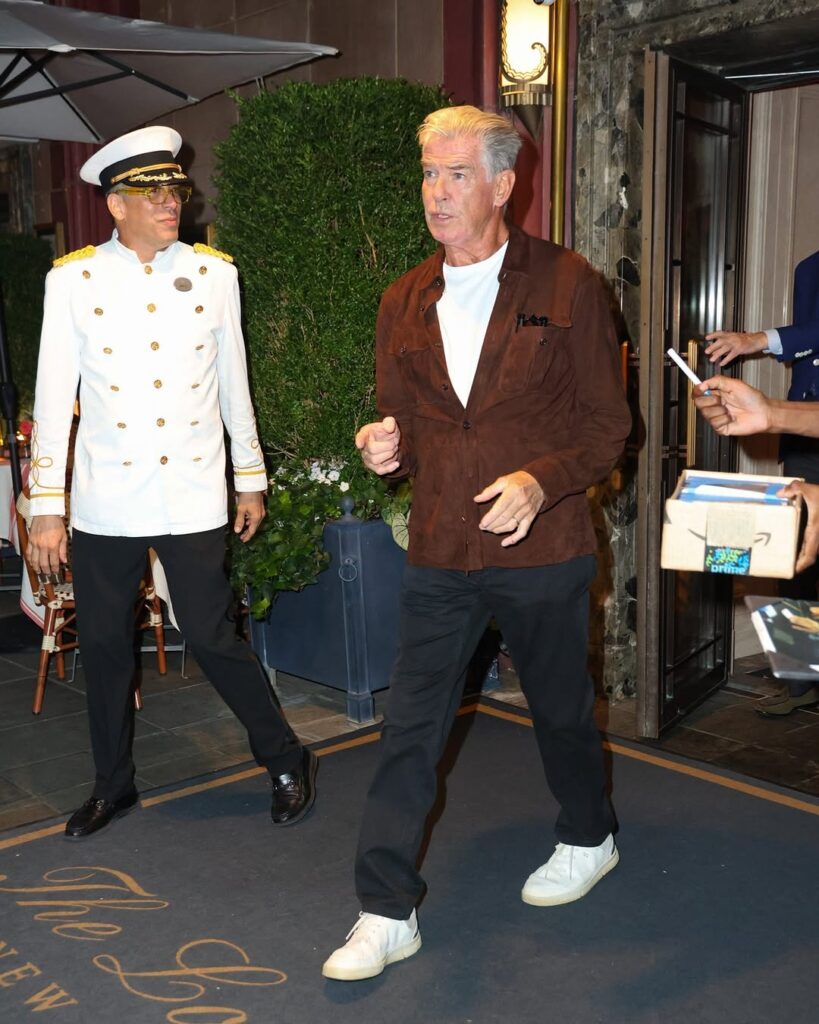 Pierce Brosnan in a brown suede overshirt, white tee, and sneakers—off-duty style with effortless polish outside The Lowell Hotel in New York.