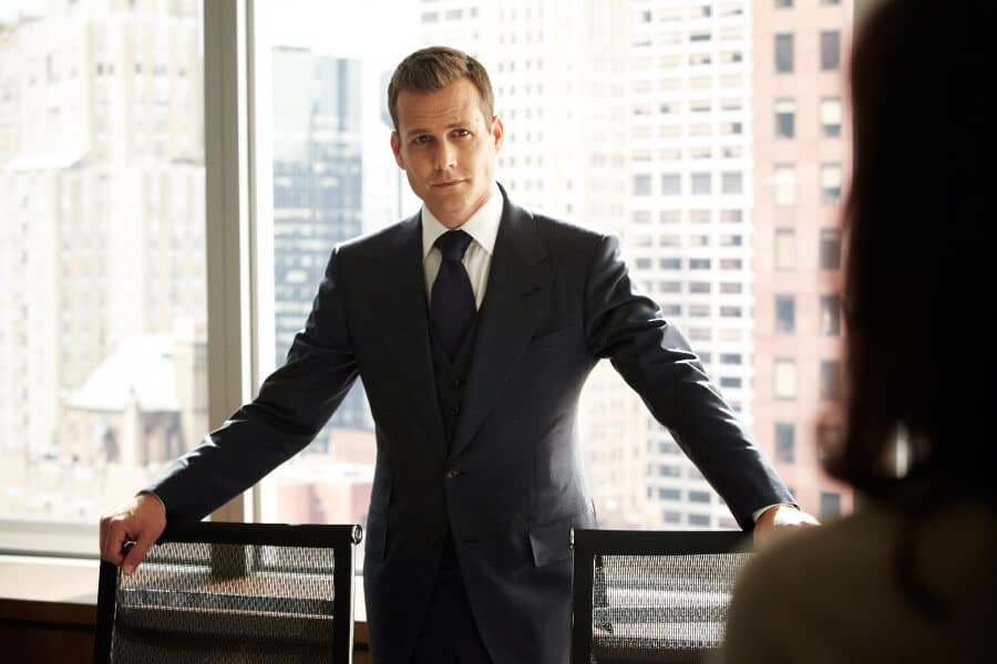 Navy three-piece suit with peak lapels, white shirt and navy tie, worn by a man in a city office