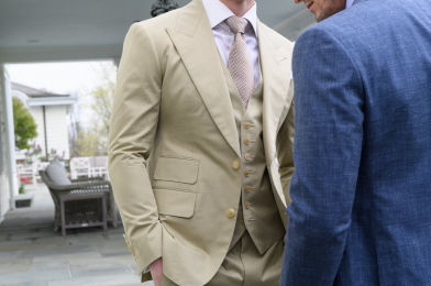 Tan three-piece custom suit with notch lapel, matching waistcoat and tie, styled with a light dress shirt in an outdoor setting, paired with a blue suit, Kentucky Derby style guide.