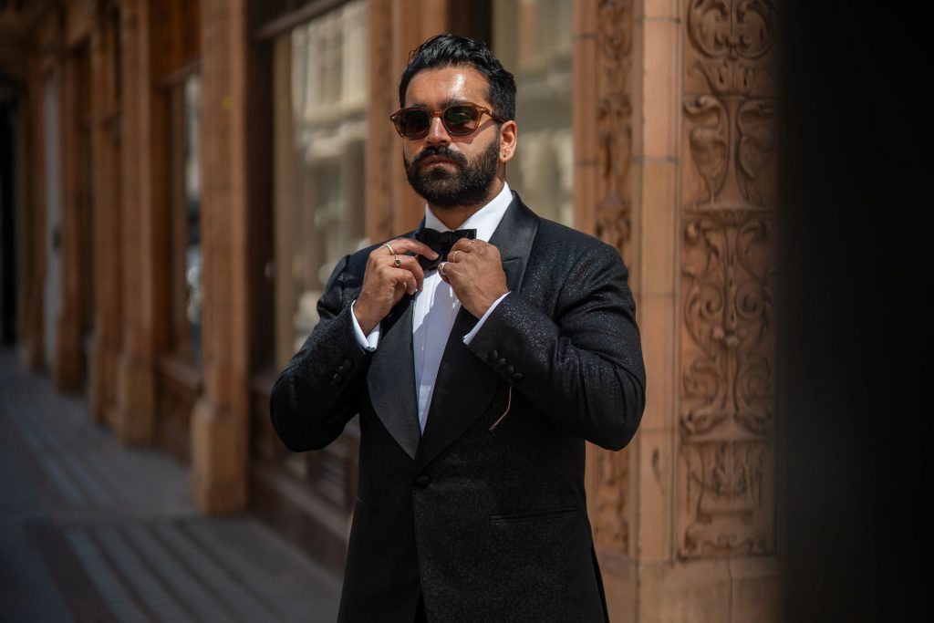 Rikesh Chauhan wearing a black tuxedo in Dormeuil Celebration for Look No. 15 of Michael Andrews Bespoke’s 20 for 20 anniversary lookbook.