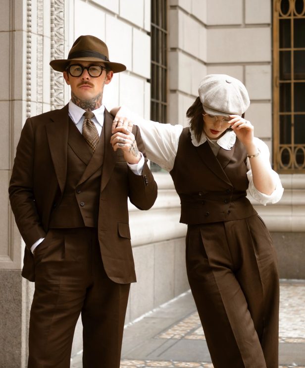 Damien and Corinne Broderick wearing coordinated brown tailored looks in Dormeuil 4 Elements for MAB’s 20 for 20 anniversary lookbook.
