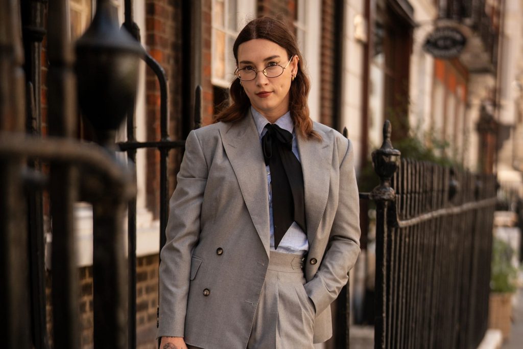 Brit Bones wearing a grey herringbone suit in Dormeuil Pashmina for Look No. 12 of Michael Andrews Bespoke’s 20 for 20 lookbook.