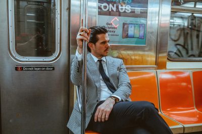 Cory Sylvester seated on a New York City subway wearing a black-and-white tailored jacket in Dormeuil Echo for MAB’s 20 for 20 lookbook.